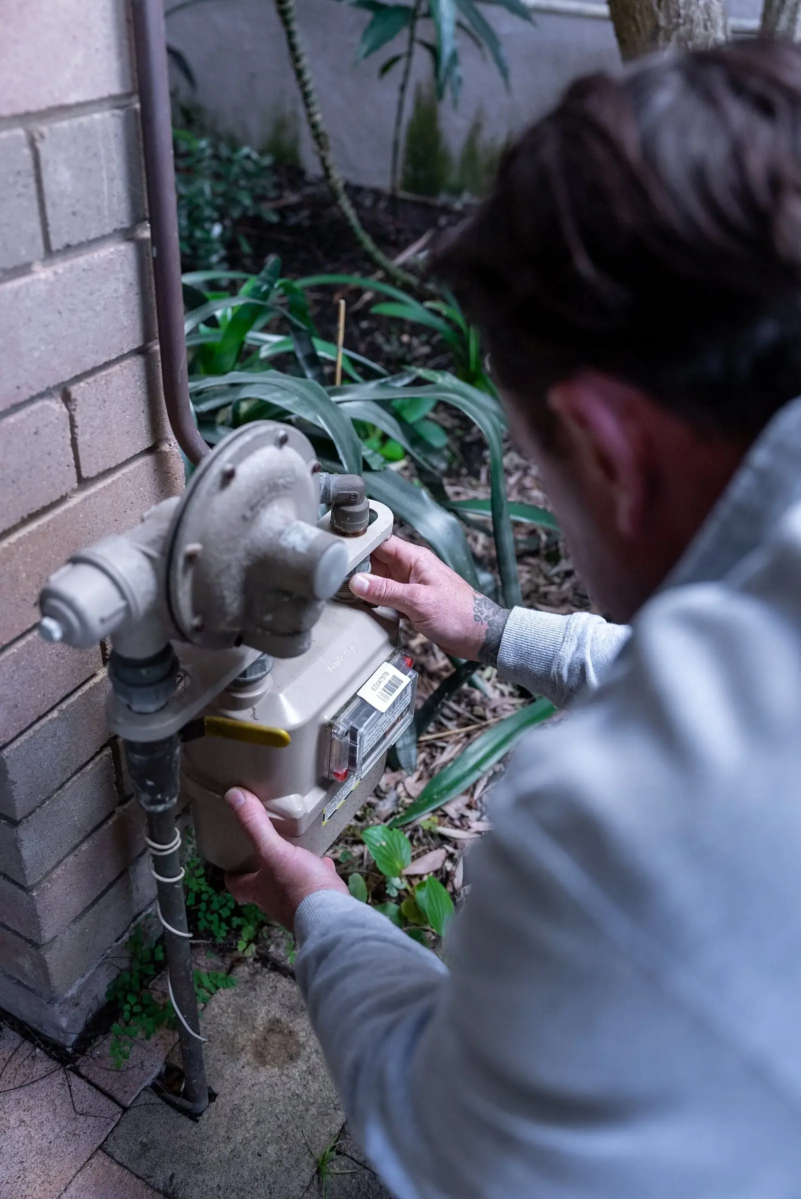 Plumber's hands on a gas meter and regulator