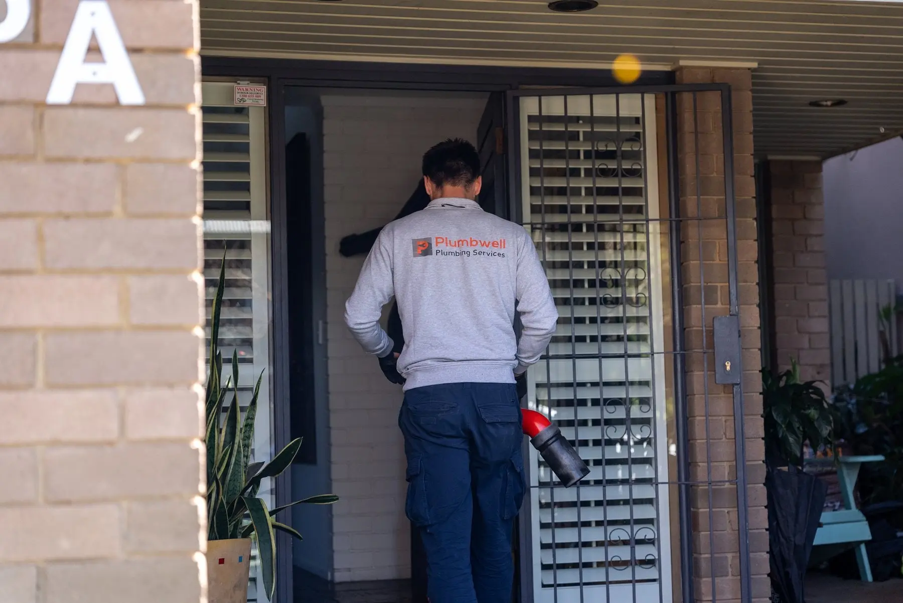 Plumber knocking at a customer's front door with his tools