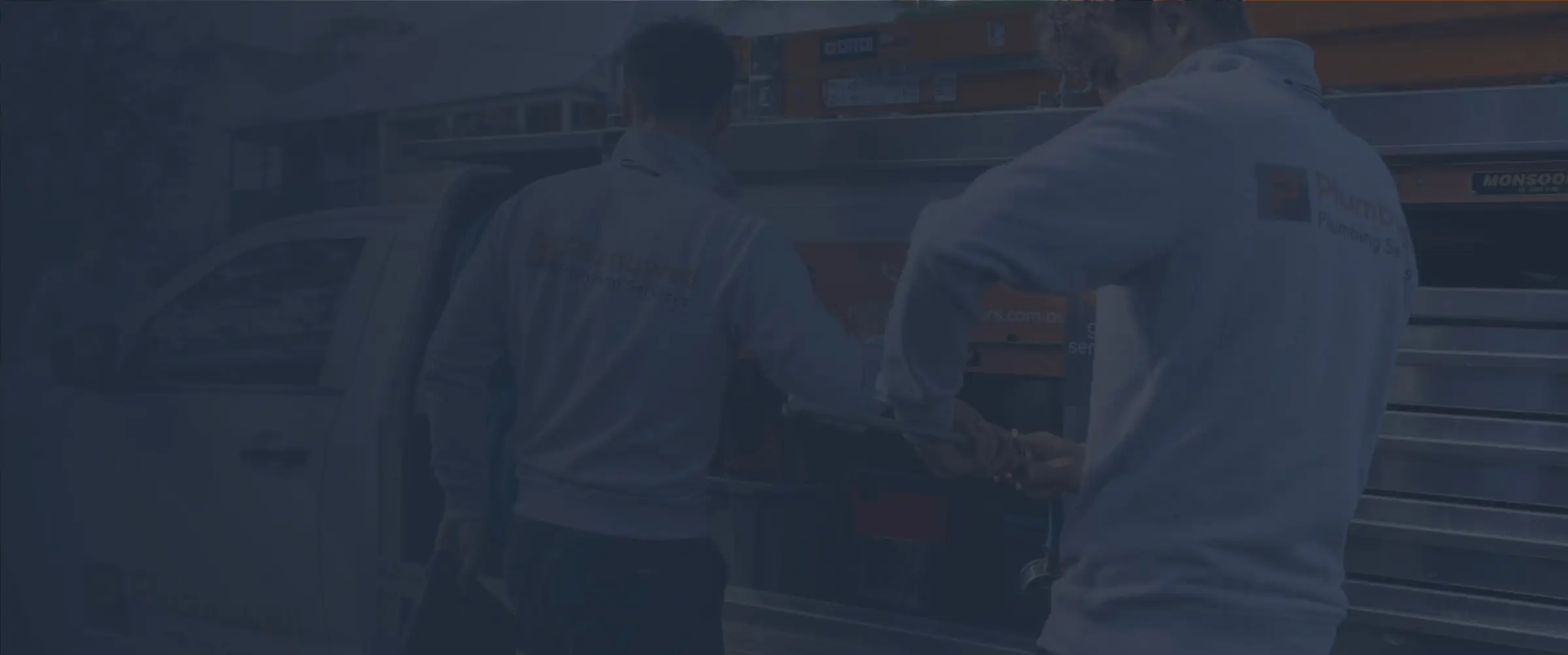 Two plumbers taking tools from the drawers of their service truck