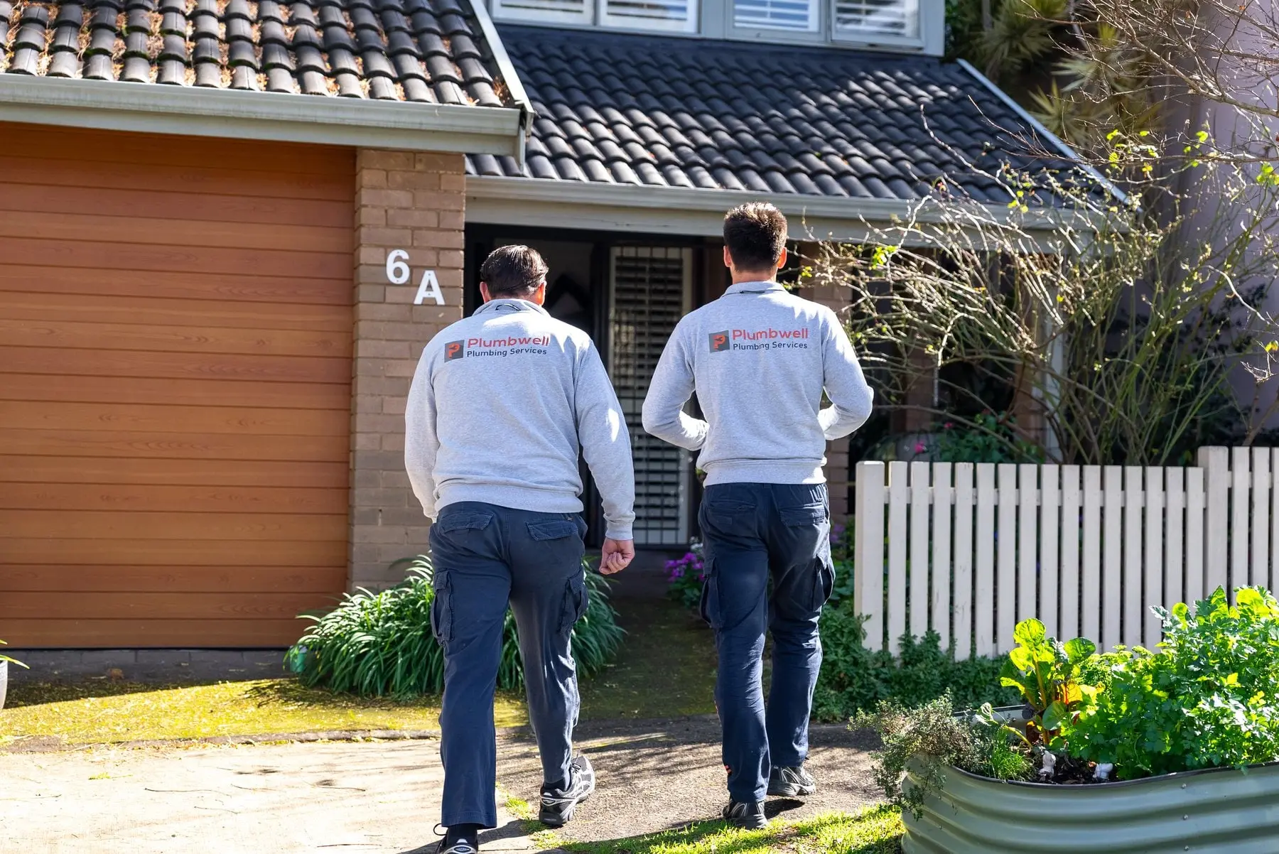 Two plumbers walking up the driveway to a customer's home